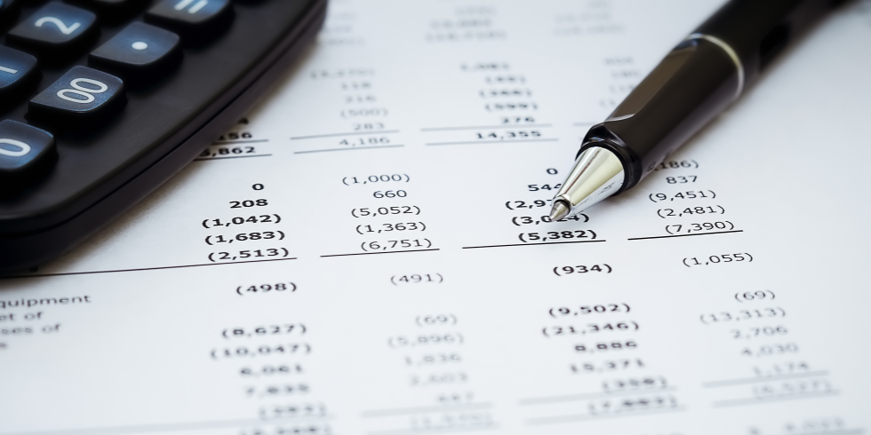 Financial Reports_980x490 Pen and calculator on top of financial report