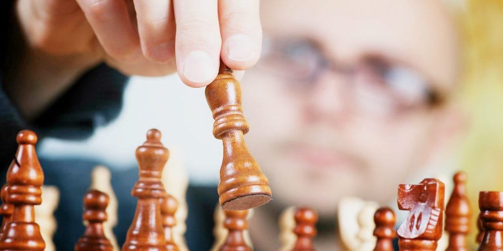 the-strategic-question A man playing chess with the pieces in the foreground